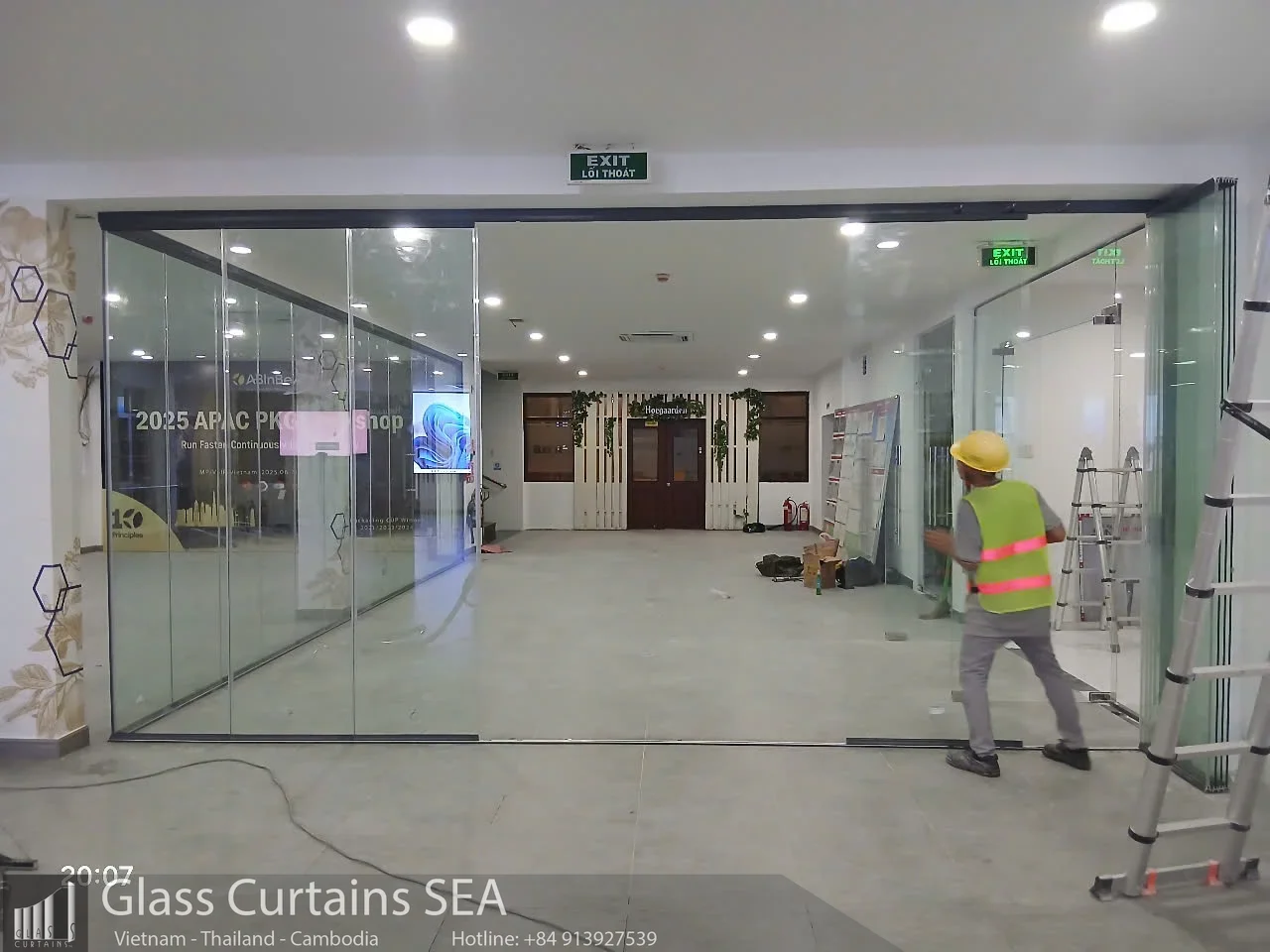 Công nhân lắp đặt cửa kính xếp trượt cho nhà ăn nhân viên
