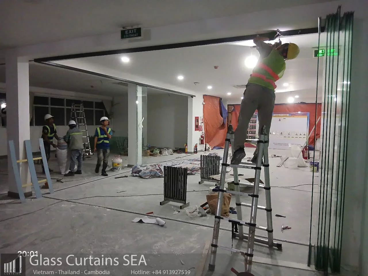Thợ lắp đặt cửa kính xếp trượt tại nhà máy, công nhân làm việc trên thang