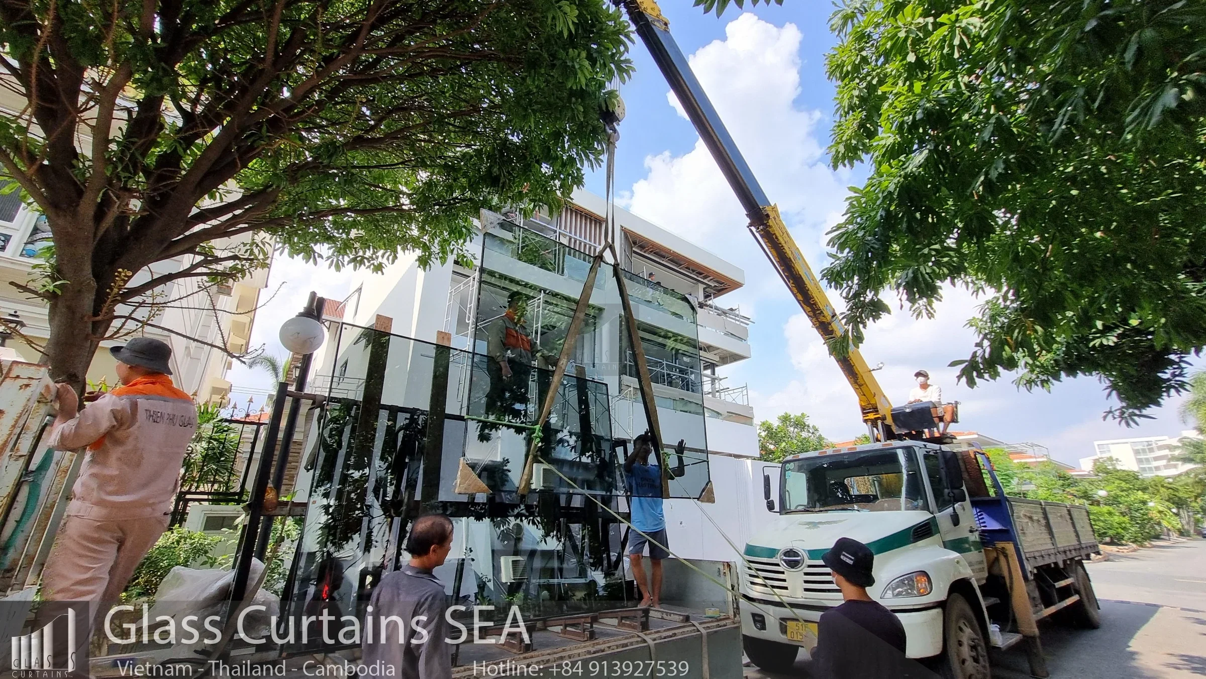 Công nhân dùng xe cẩu lắp kính cường lực cho tòa nhà hiện đại